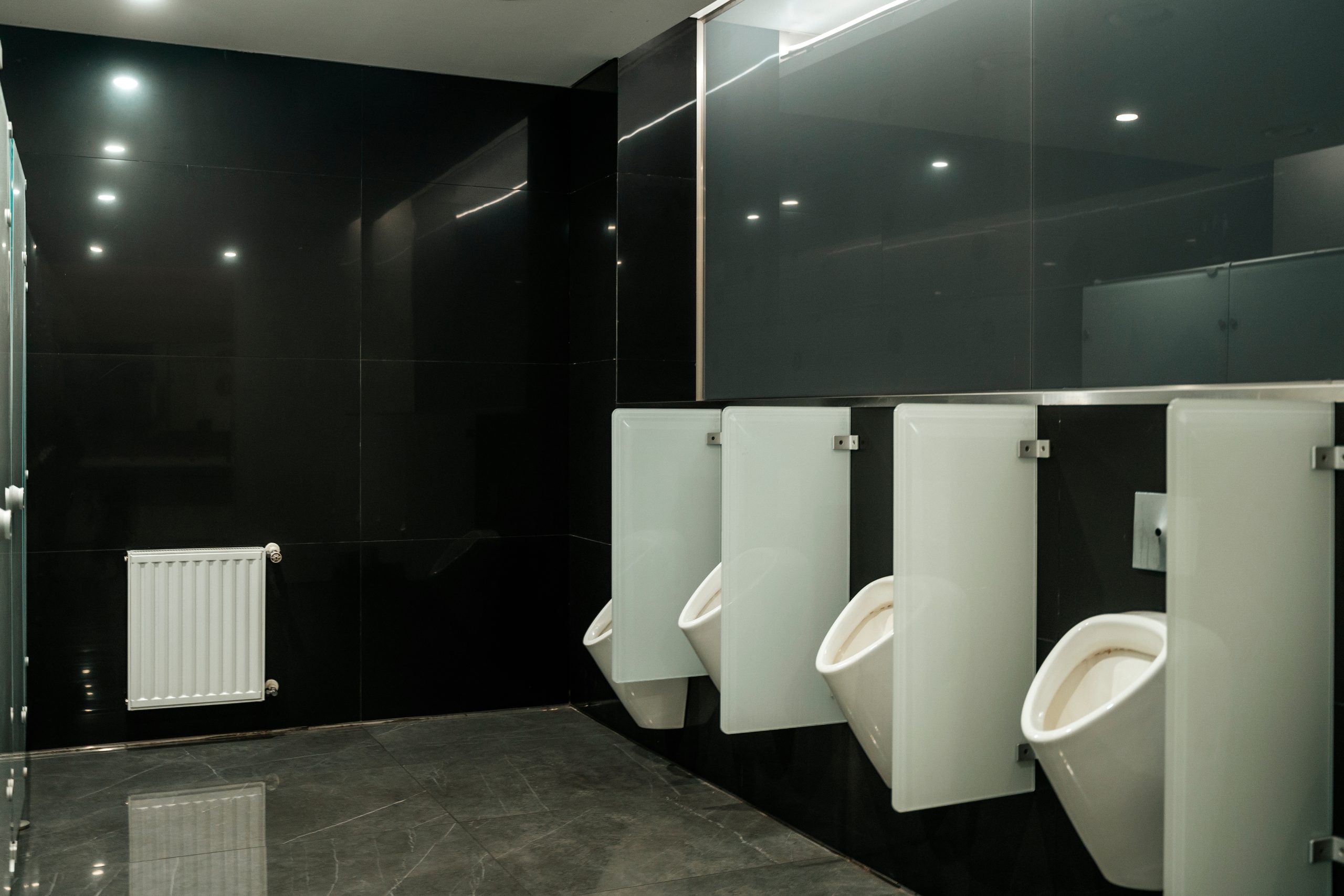 Modern Public Restroom Interior with White Urinals and Black Tiled Walls. High quality photo